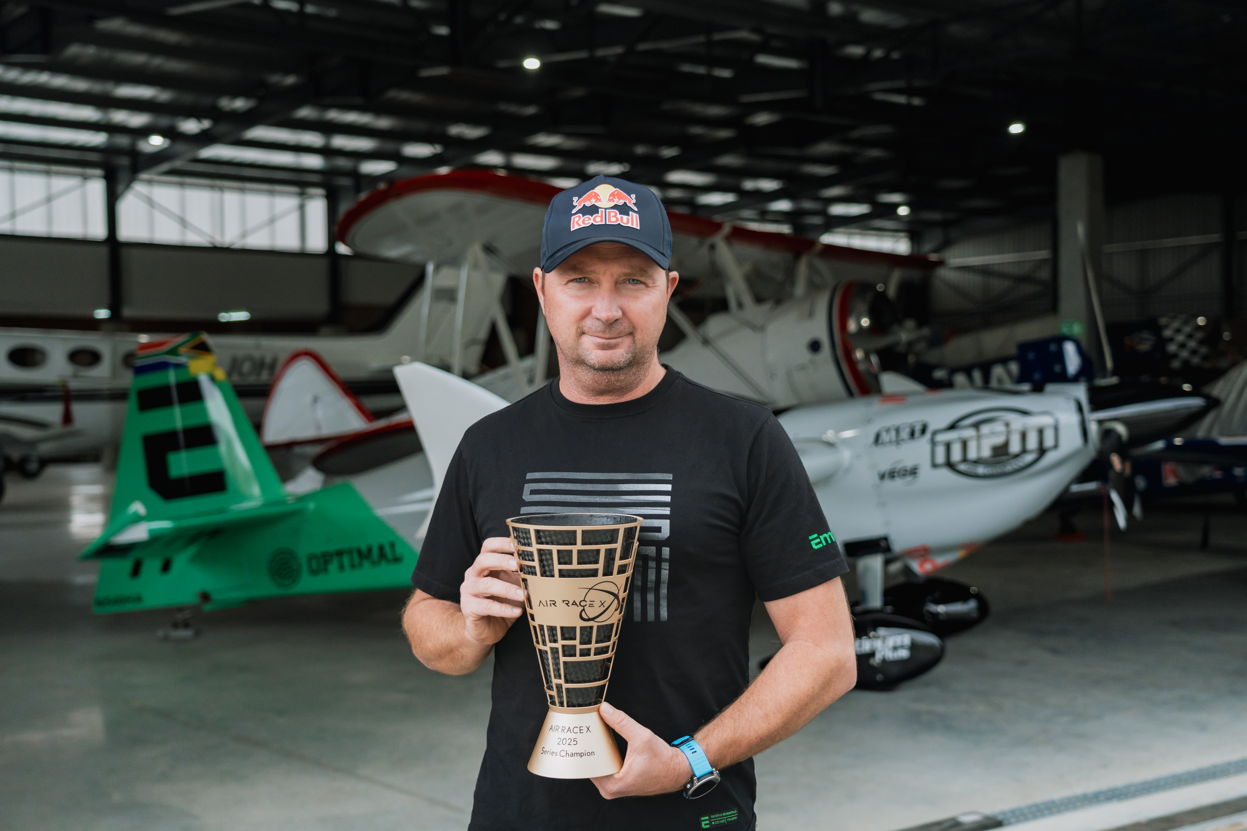 Air Race X plane in hangar + Patrick Davidson and 2025 Trophy